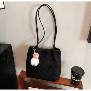 Détail d'un sac à bandoulière noir pelucheux avec texture douce et breloque poupée
