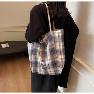 Sac fourre-tout à carreaux porté par un mannequin dans un intérieur moderne chic