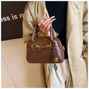 Detailed macro view of vintage brown boston bag with gold hardware and bell charm detail