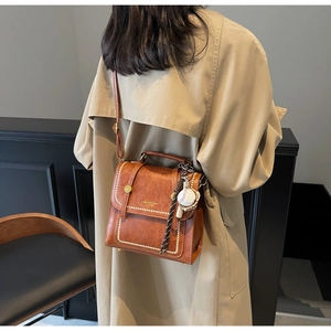 Detail of vintage brown leather bag with white rivets and baseball charm accessory