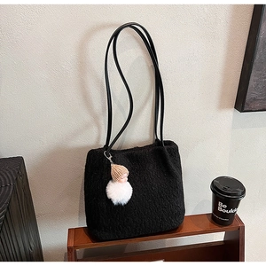 Détail du sac cabas en peluche noire avec pendentif poupée et fines anses en cuir