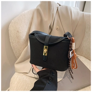Close-up of black matte bucket bag featuring a gold metal lock and braided rope pendant