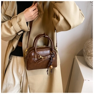 Detail of vintage brown leather boston bag with golden hardware and metallic charm