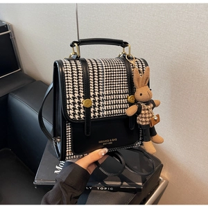 Detail of retro houndstooth handbag with gold buckle and cute brown bunny charm