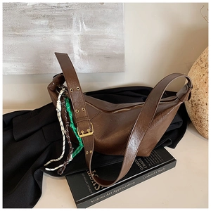 Detail of dark brown crescent hobo bag with textured faux leather and colorful woven ropes