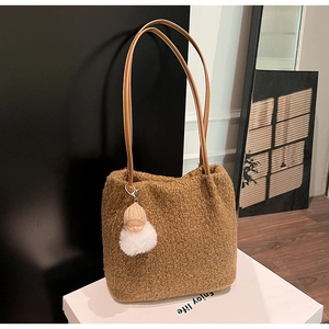 Gros plan sur un sac cabas en peluche marron avec texture fausse fourrure et anses en cuir