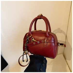 Vue détaillée du sac vintage bordeaux avec finitions dorées et pendentif clochette