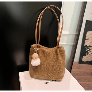 Détail d'un sac cabas en peluche marron avec pendentif poupée et bandoulière en cuir