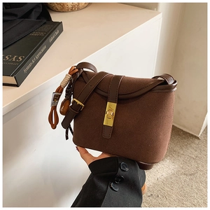 Detail of vintage brown suede bucket bag with gold twist lock and woven strap decoration