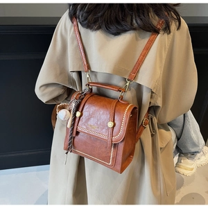 Detail of vintage brown leather backpack featuring gold clasp and baseball charm