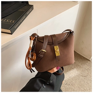 Detailed shot of brown frosted bucket bag with gold metal clasp and woven knot charm