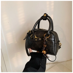 Détail du sac Boston rétro noir avec boucle dorée et pendentif clochette décoratif