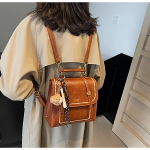 Close-up of vintage brown leather backpack with gold buckle and fashion logo detail