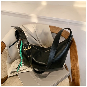 Detail of black hobo bag with lychee texture and colorful braided rope on wooden chair