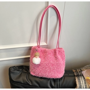 Détail d'un sac cabas en peluche rose vif avec un charm poupée et une longue bandoulière