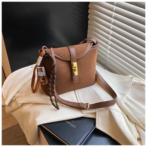 Detail of vintage brown suede crossbody bag with gold metallic buckle and woven strap