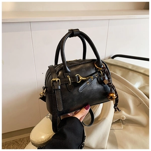 Détail de la texture en cuir noir mat et du mors de cheval vintage doré sur le sac