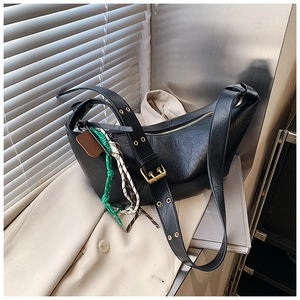 Detail view of black half-moon crossbody bag with woven pendant and gold buckle