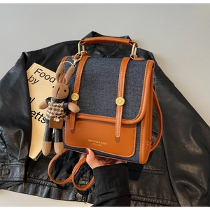Detail of retro denim backpack with leather trim and cute rabbit doll keychain