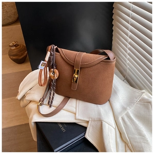 Detail of vintage brown matte bucket bag with golden twist lock and charm on white blazer