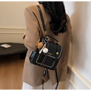 Detail of black leather flap bag with white contrast stitching and gold lettering