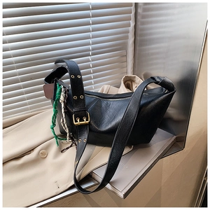 Close-up of black half-moon bag featuring golden metal eyelets and woven rope pendant