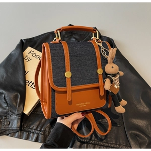 Detail of color-block brown leather and denim backpack with a cute woven bunny charm