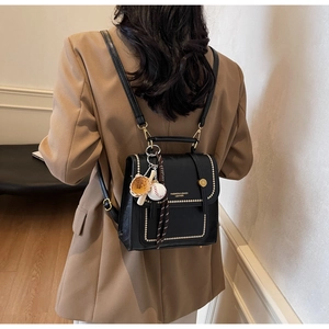 Detail of black leather mini backpack with gold rivets and baseball charm on a model