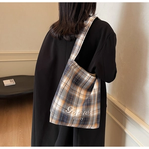 Vue détaillée du grand sac cabas en toile à carreaux porté sur un blazer noir