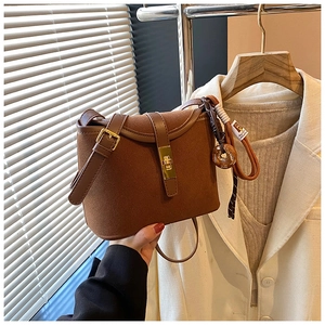 Detail of vintage brown suede bucket bag featuring golden twist lock and leather strap