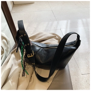 Detail of black Hobo bag with wide strap, gold hardware and woven rope charm