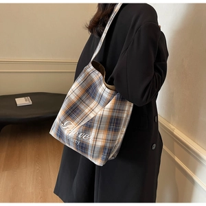 Détail d'un cabas en toile à carreaux avec imprimé Forever Party porté par un mannequin