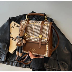 Close-up of vintage plaid backpack with leather trim and a cute rabbit pendant