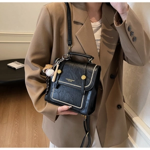 Detail of black PU leather crossbody bag with studs and creative baseball charms