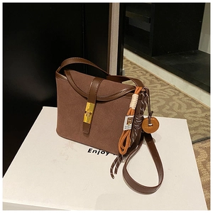 Detail of vintage brown frosted leather bucket bag with gold clasp and woven charm