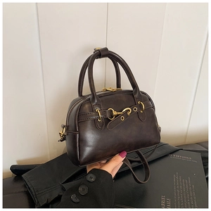 Détail d'un sac Boston vintage marron foncé avec boucle mors dorée élégante en gros plan