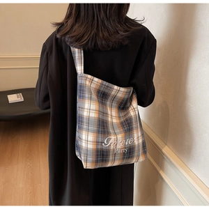 Sac fourre-tout en toile à carreaux porté par un mannequin dans un salon moderne