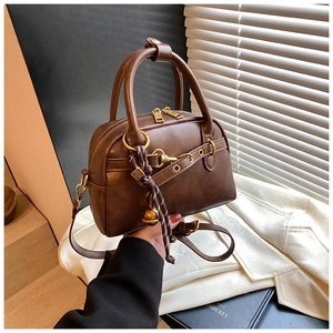 Détails d'un sac Boston vintage en cuir marron avec rivets dorés et breloque tressée