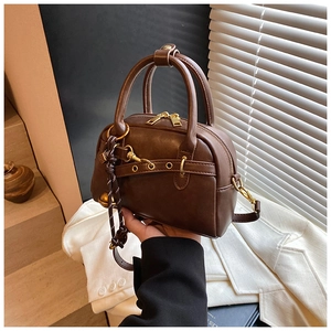 Détail d'un sac à main vintage en cuir marron avec bandoulière à œillets et zip doré