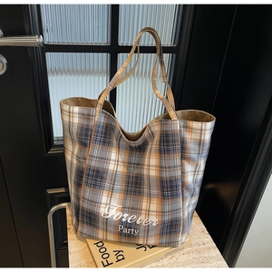 Détail d'un sac cabas en toile à carreaux bleu et orange avec une inscription imprimée