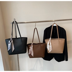 Three lychee grain leather tote bags with silk scarves hanging on a metal rack