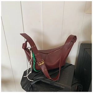 Detail of burgundy crescent shoulder bag with gold buckle and woven rope charm detail