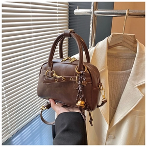 Détail du sac à main rétro en cuir PU marron avec garniture dorée antique et pendentif boule