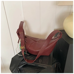 Detail of burgundy half-moon bag featuring wide grommet strap and retro gold hardware