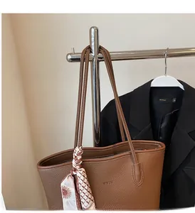 Detail of brown lychee grain leather tote with WWTU logo and floral silk scarf handle