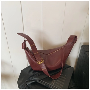 Close-up of deep red vintage leather bag with adjustable wide strap and gold hardware