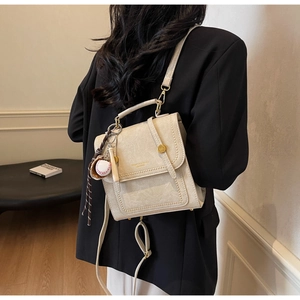 Detail of cream vintage bag with baseball charm on model showing its texture and scale