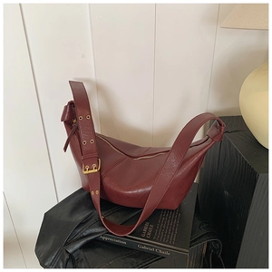 Detail of dark burgundy hobo bag with gold eyelet strap and natural leather texture