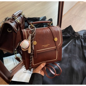 Detail view of brown vintage backpack with gold studs and baseball charm decor
