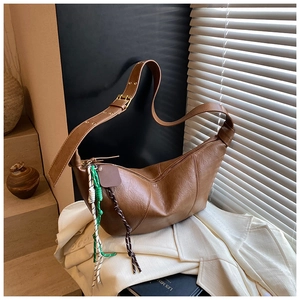 Close-up of brown crescent bag with pebble leather texture and braided rope charm